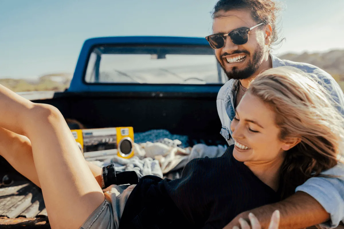 couple in back of a van on a road trip smiling and laughing