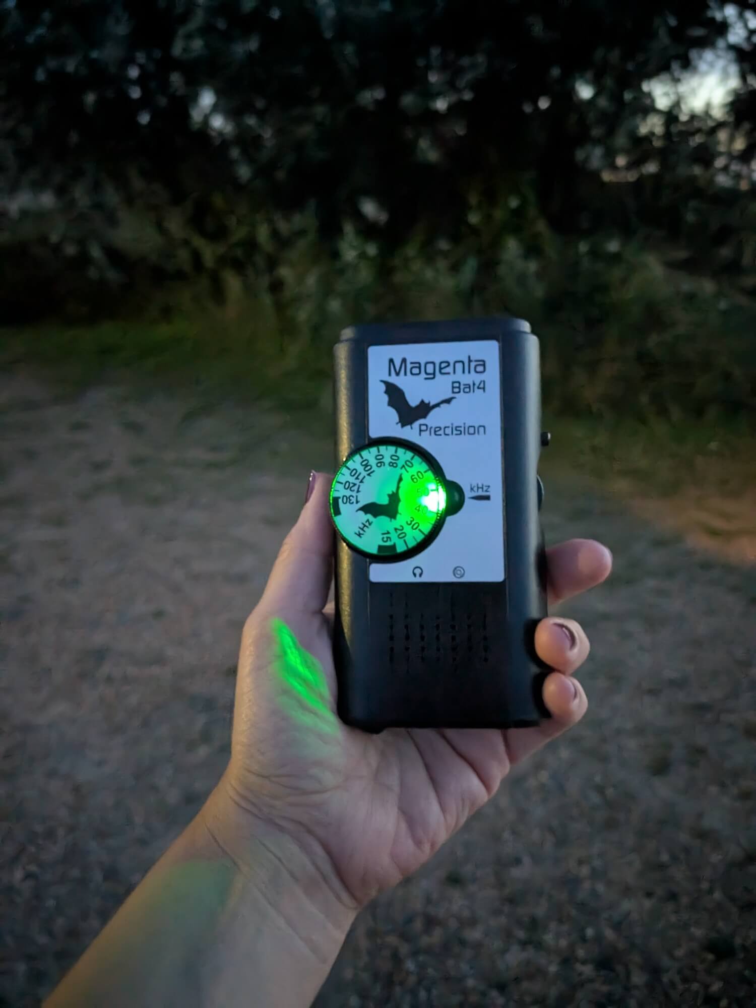 a hand holding a device with a green light